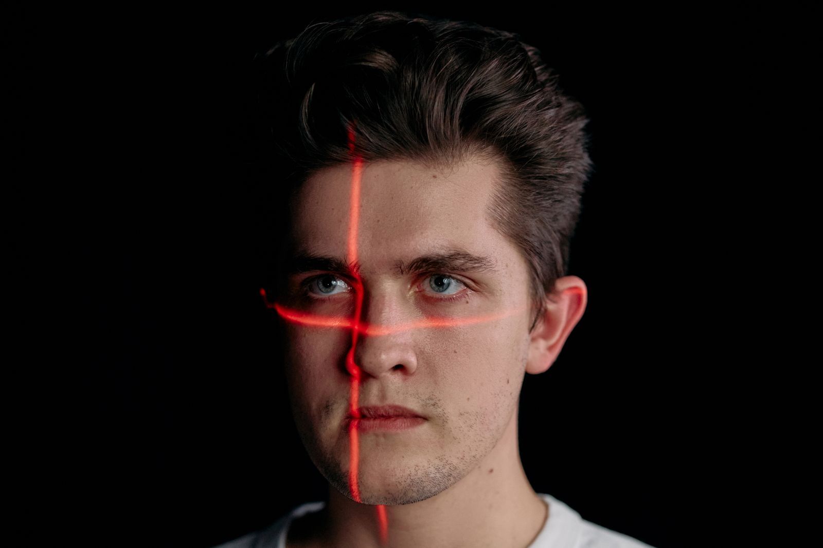 Tvář člověka s červenou skenovací mřížkou — biometrie, deepfake a zneužití AI